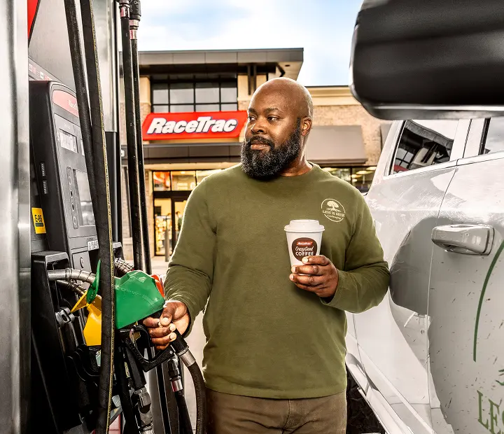 pro driver pumping gas holding a RaceTrac coffee